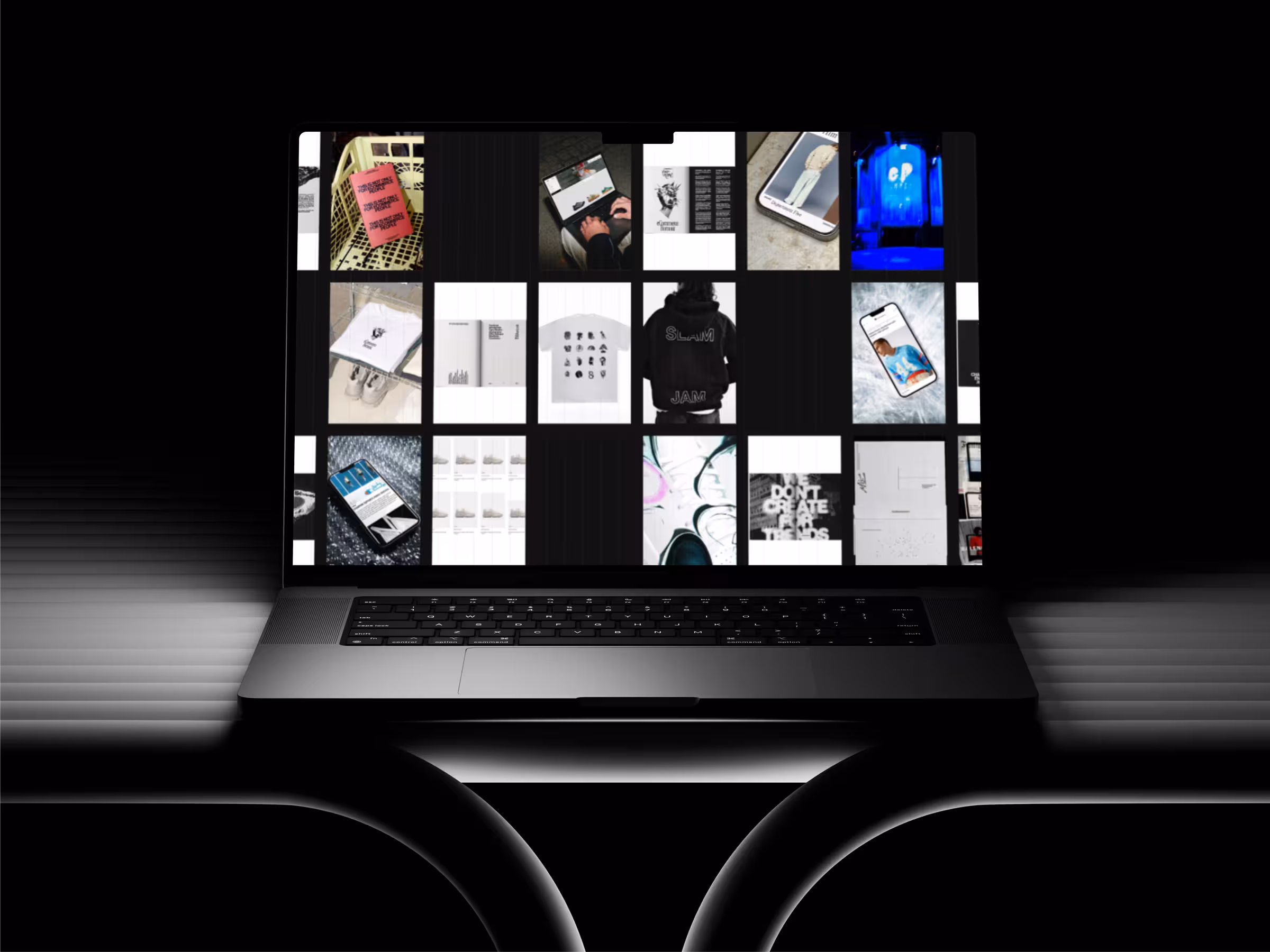 Laptop on white table shows holographic PVC hoodie design on screen in a monochrome room.